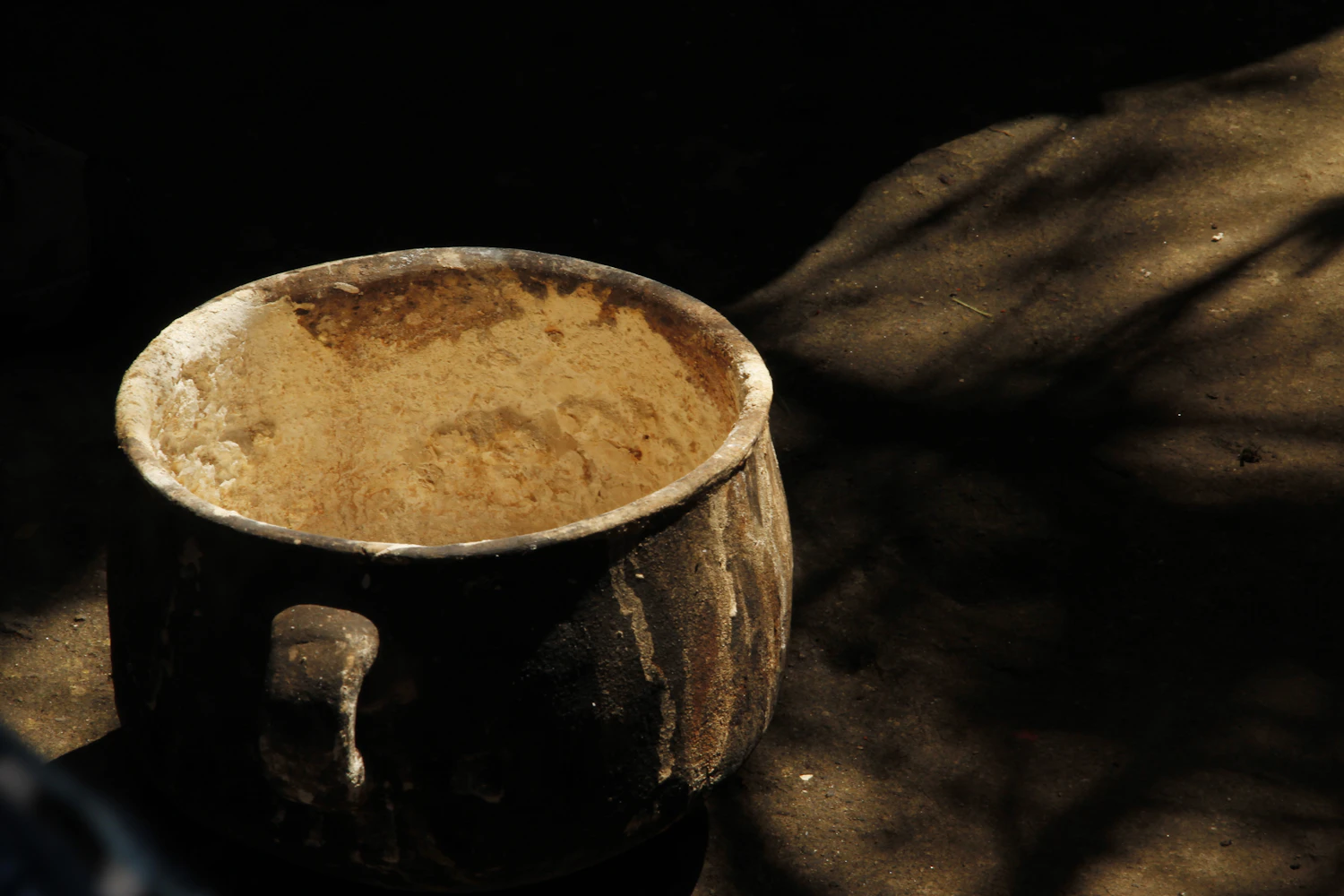 A battered metal preserving pan in hard side light