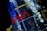 A close-up view of a highly reflective metallic structure, displaying the NASA logo prominently in red. The surface is crinkled, suggesting a foil-like texture, with a blend of silver and blue hues. Yellow structural components are visible, adding contrast to the overall design.