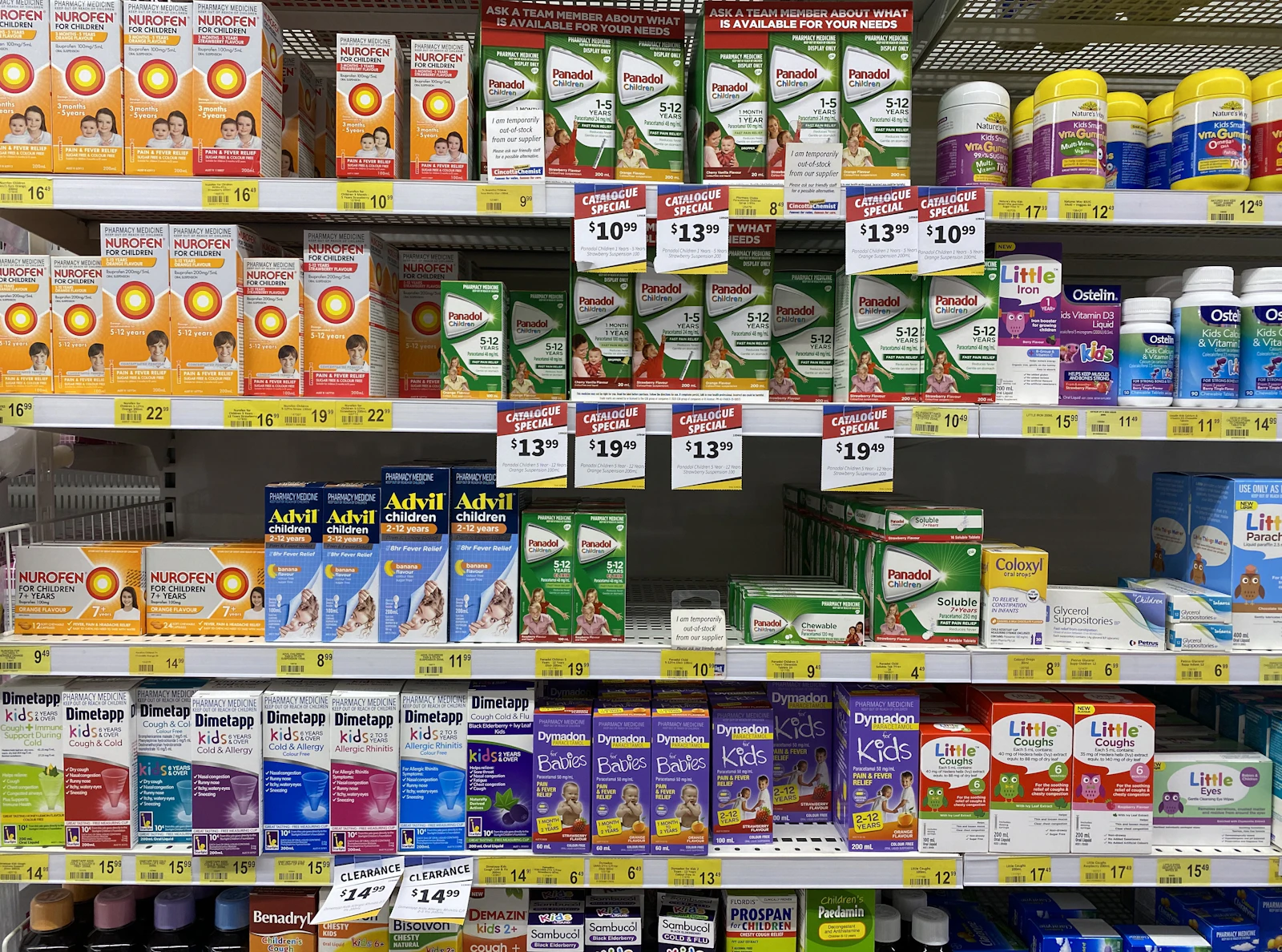 Pharmacy shelves stocked with over-the-counter medicine boxes and bright yellow price tags.