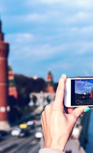 person holding white android smartphone taking photo of tower during daytime