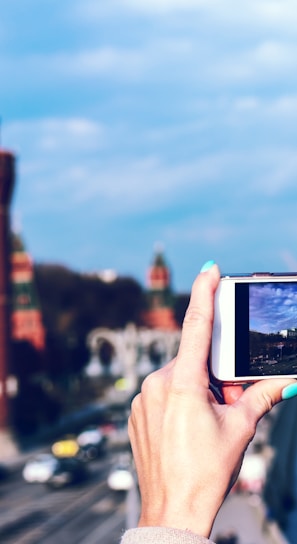 person holding white android smartphone taking photo of tower during daytime