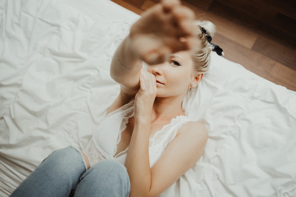 woman in white tank top lying on bed