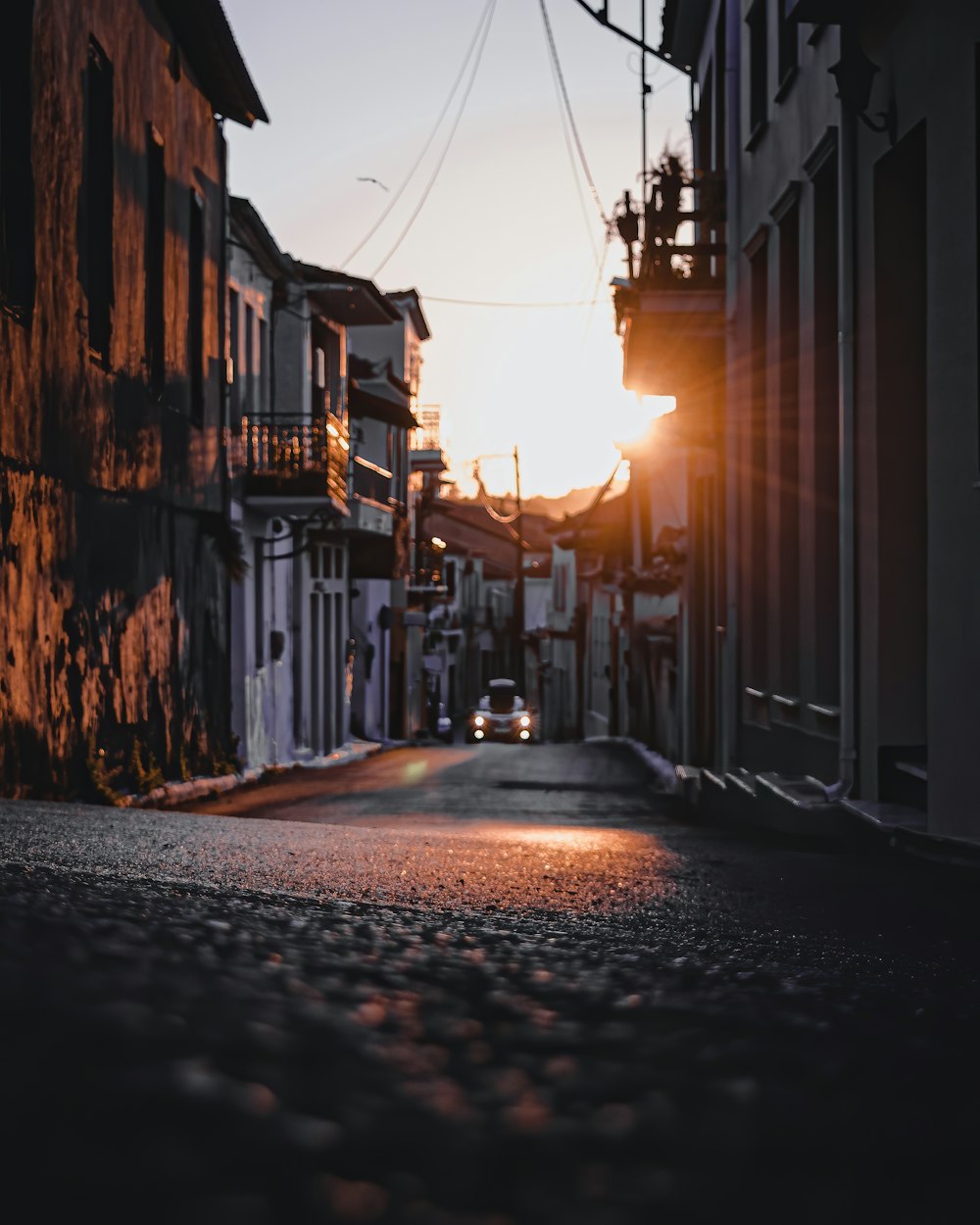 black car on road between buildings during sunset