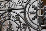 Wrought iron gate with intricate traditional design in a residential setting.