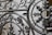 Ornate wrought iron gate featuring intricate patterns and designs with a mix of curved and linear elements. The craftsmanship includes floral and leaf motifs, highlighting a vintage or historical style.
