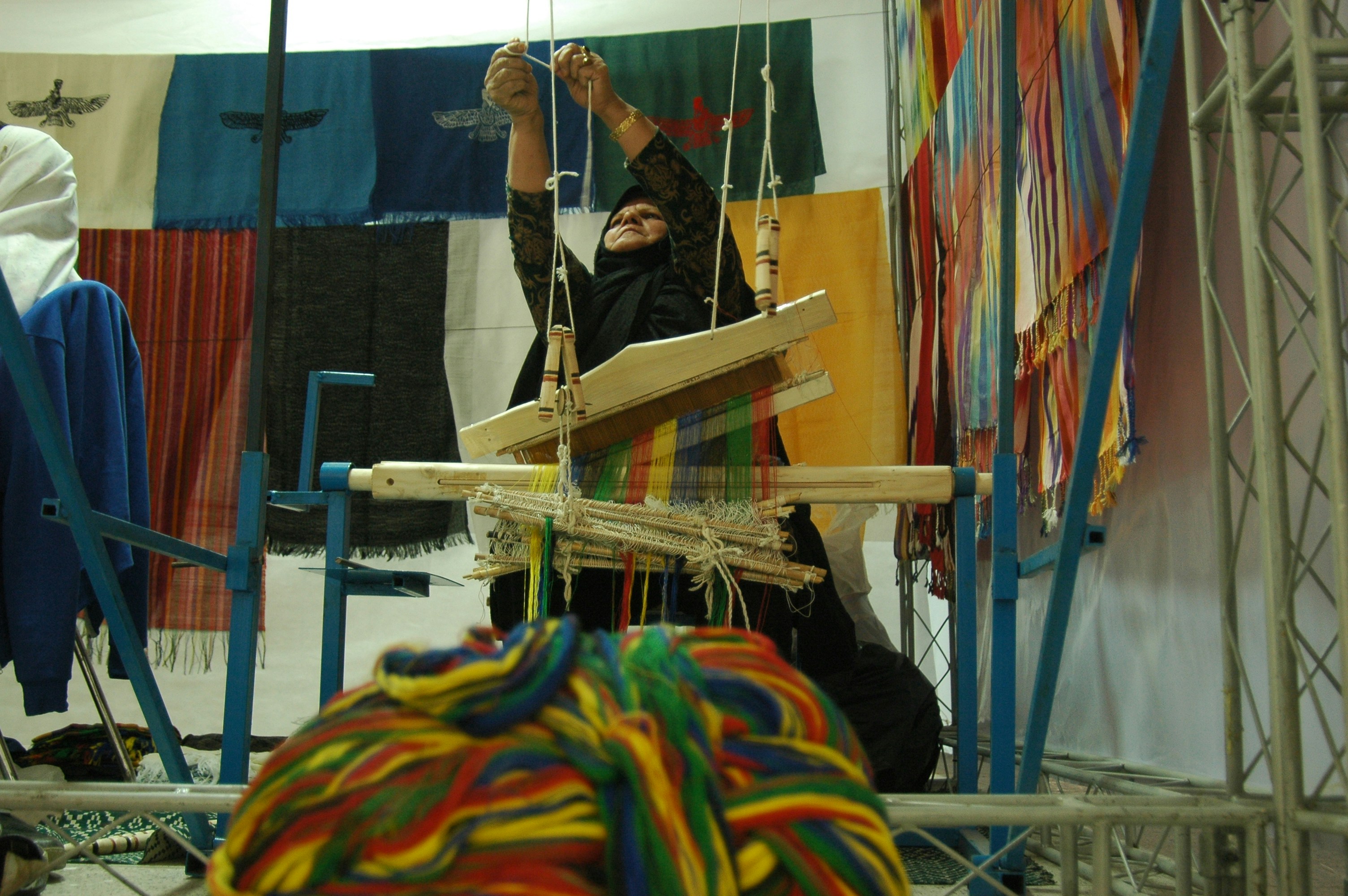 Person working on a stretched fabric frame with colorful yarn, hands-on rug making in progress.