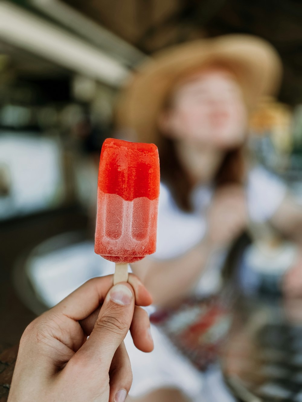 Persona sosteniendo paleta helada roja