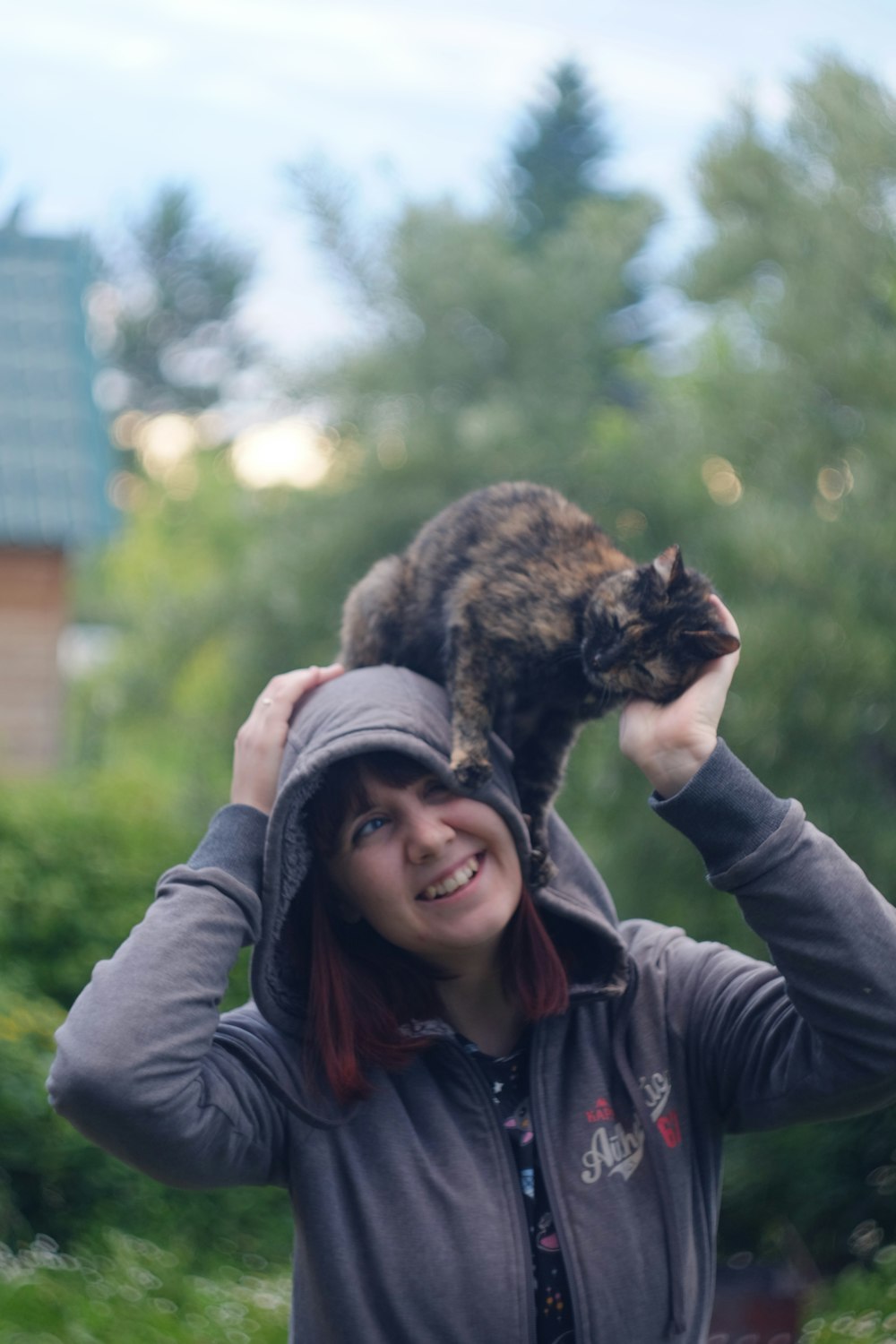 woman in black leather jacket holding brown tabby cat