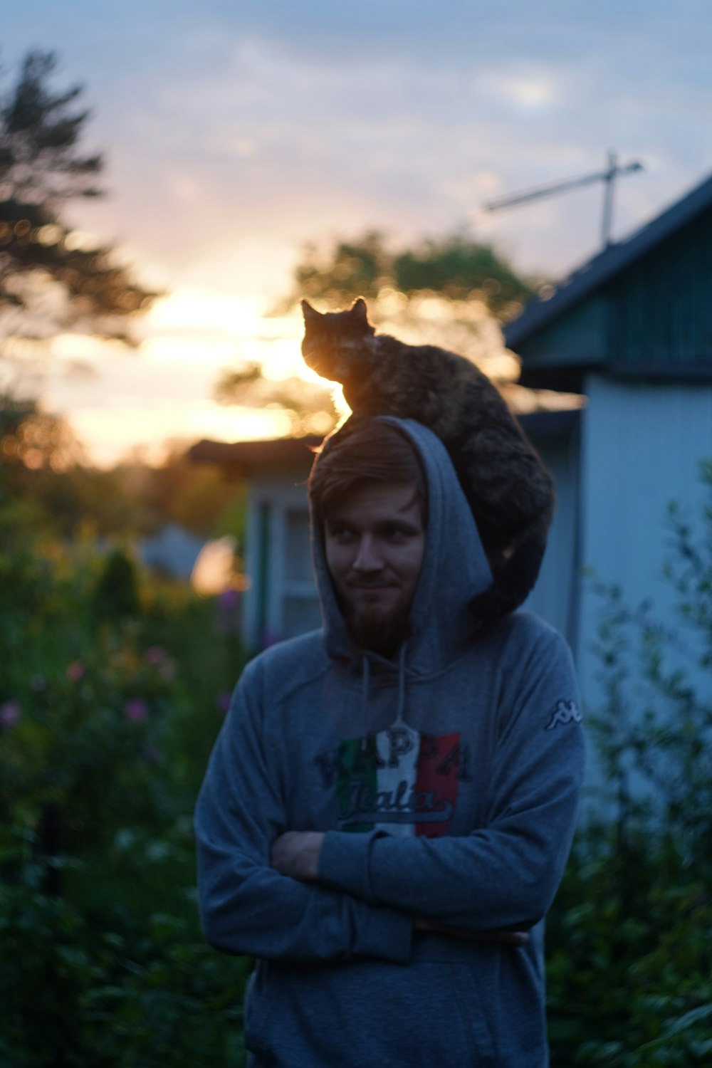 man in gray hoodie with orange tabby cat on his head