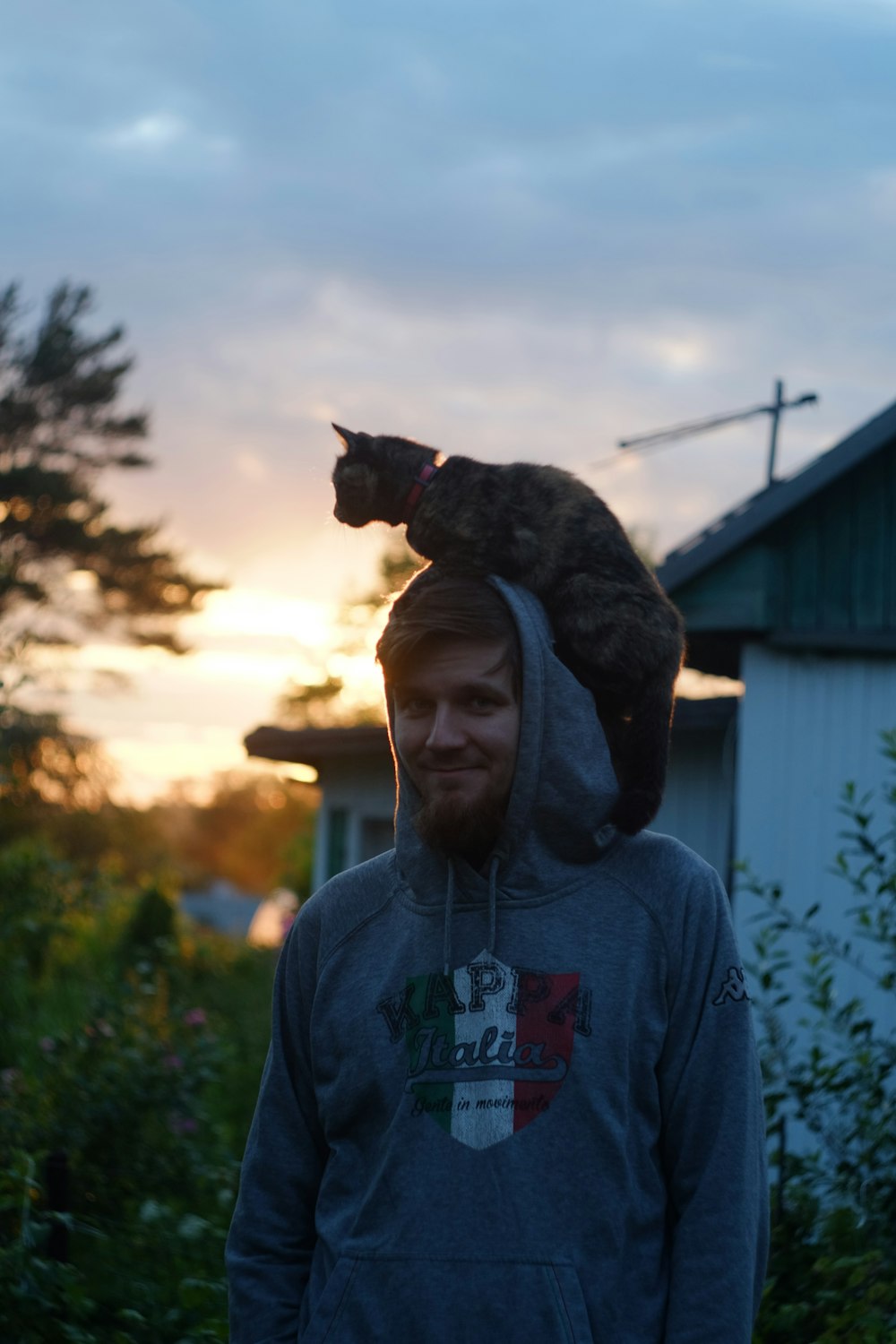man in gray hoodie carrying black cat
