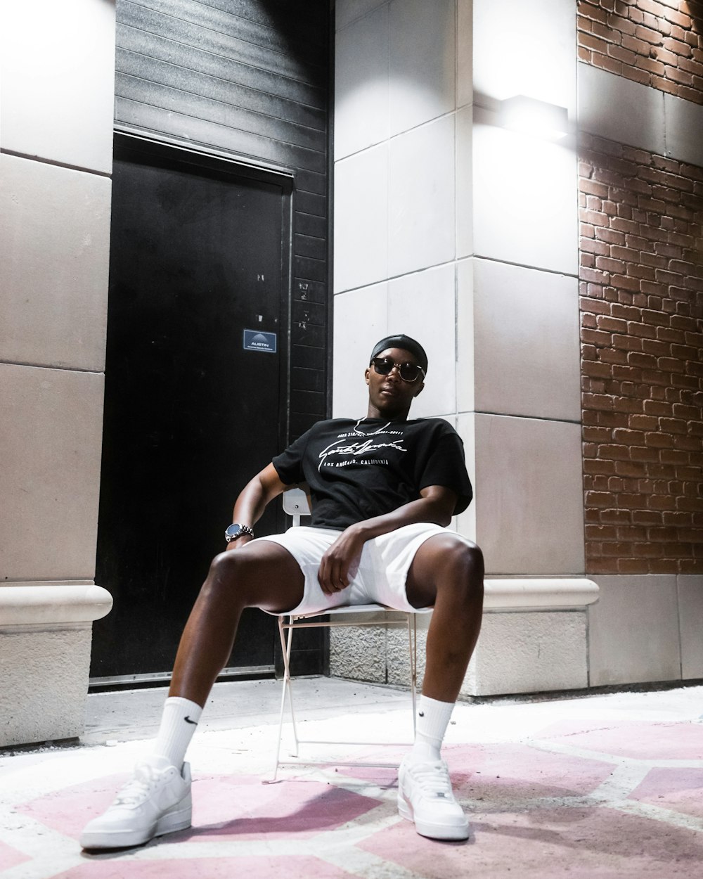 man in black t-shirt sitting on white plastic chair