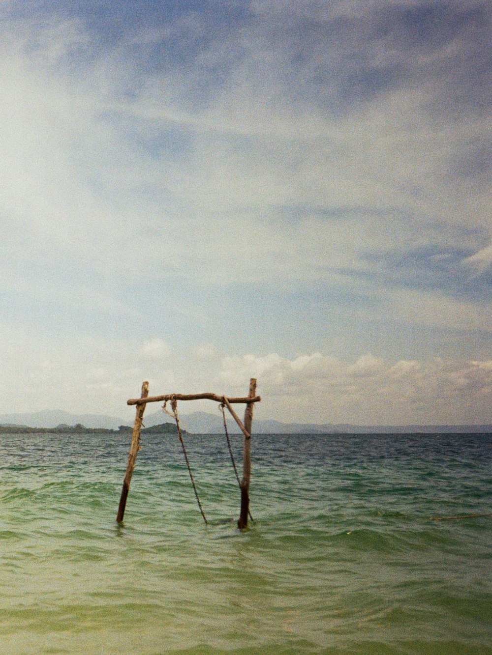 brown wooden post on sea under white clouds during daytime