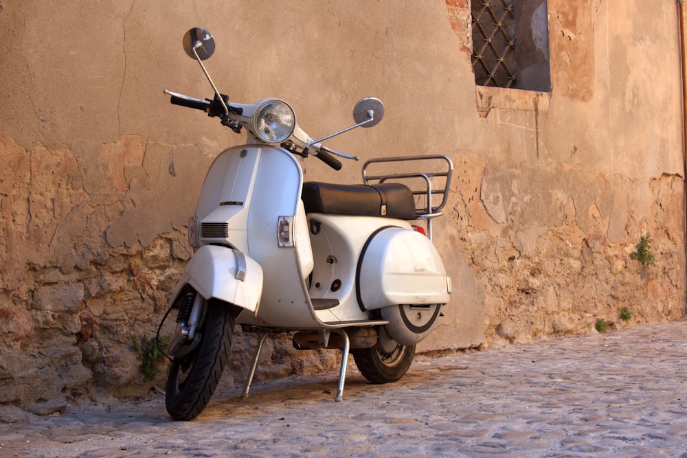 Scooter gris y negro estacionado junto a un muro de concreto marrón