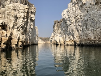 brown rocky mountain beside body of water during daytime
