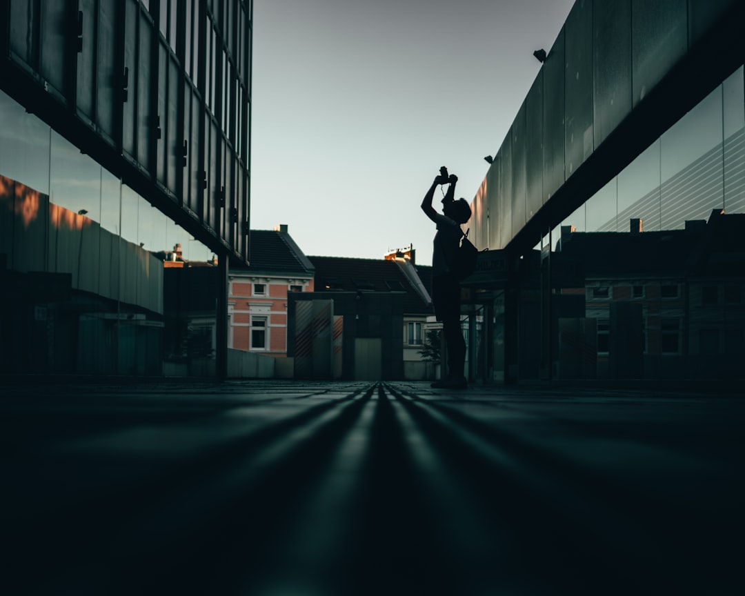 man in black jacket and pants standing on gray concrete floor during night time