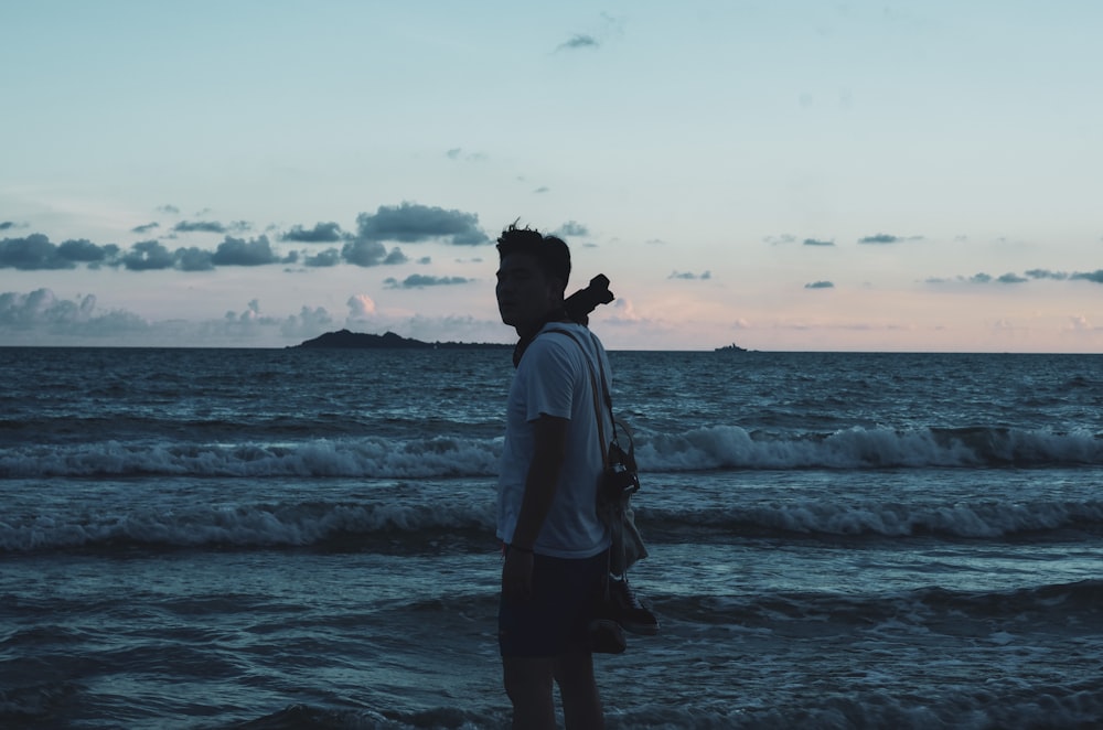 man in white shirt standing on seashore during daytime