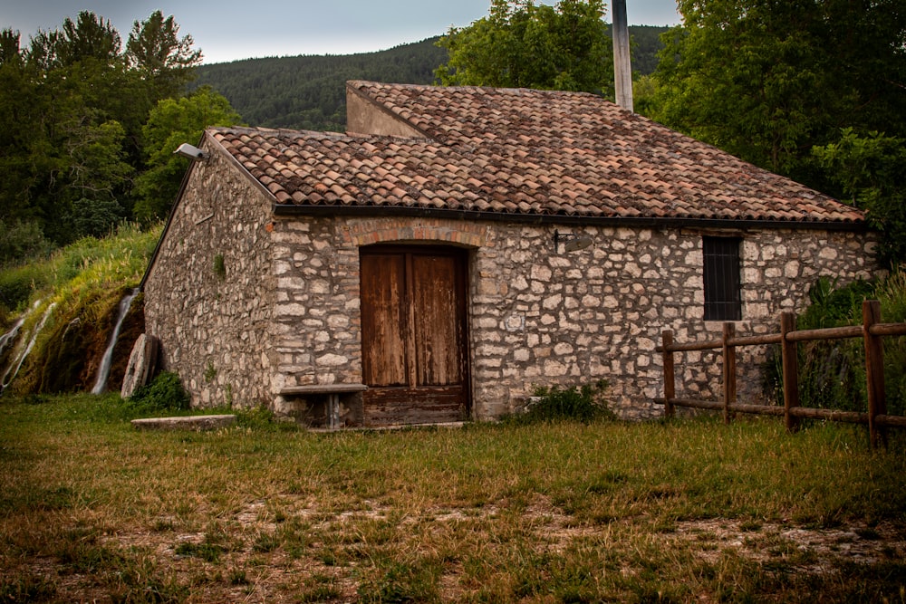 casa di mattoni marroni su un campo di erba verde durante il giorno