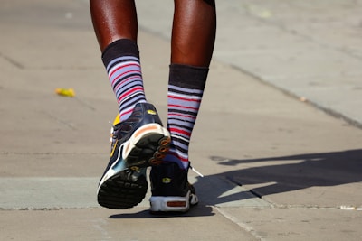 Side view of a person in black joggers with bold red stripes walking on urban pavement.