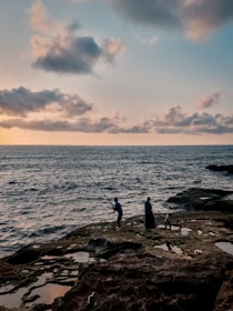 A serene fishing trip scene with a guide and family casting lines by the rocky shore.