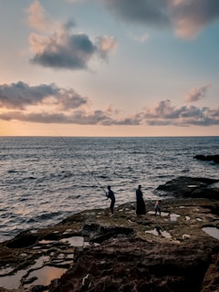 A serene fishing trip scene with a guide and family casting lines by the rocky shore.