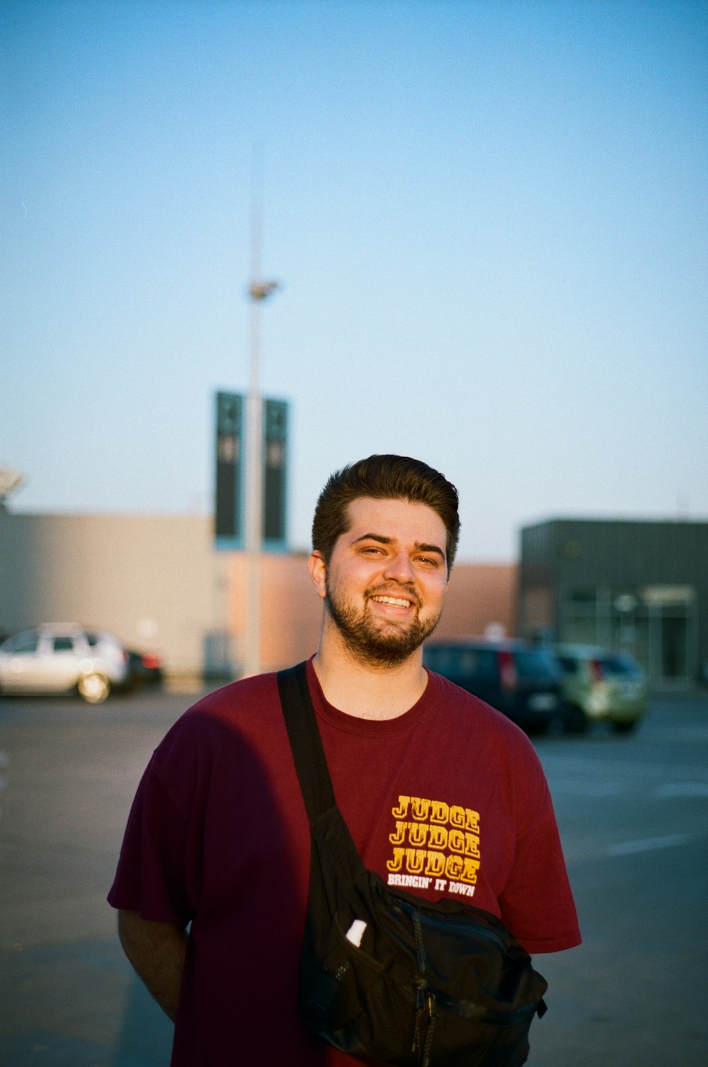 man in red crew neck shirt standing near cars during daytime