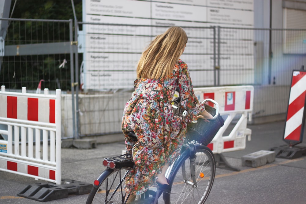 woman in white red and green floral long sleeve dress riding on bicycle during daytime