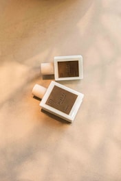A minimalist perfume bottle resting on a wooden surface with soft shadows.