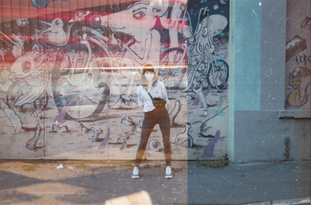 woman in white shirt and brown pants standing beside graffiti wall during daytime