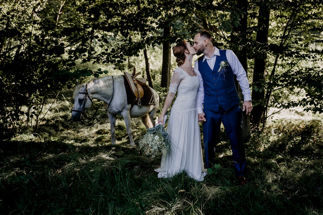 man and woman standing beside brown horse on green grass field during daytime