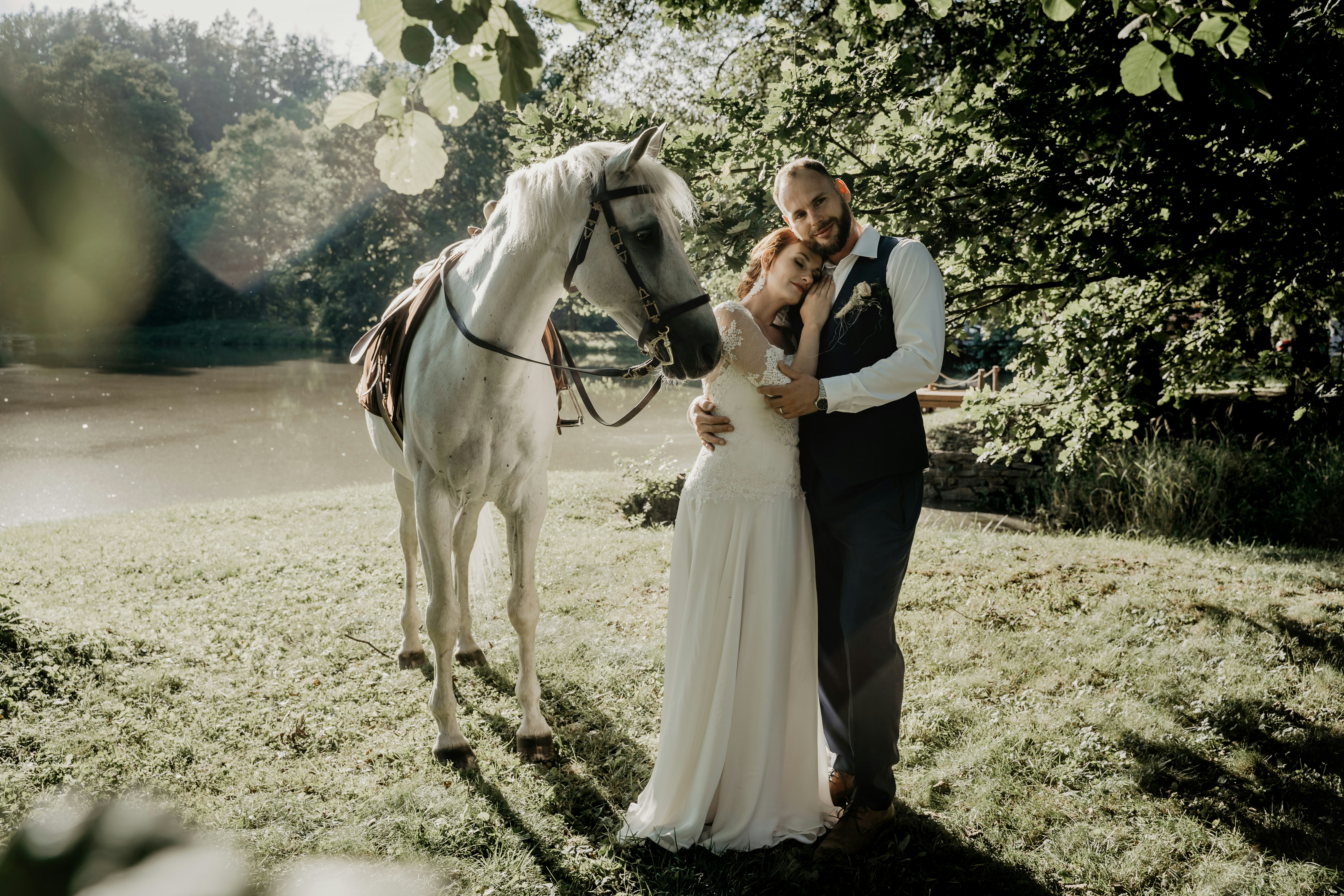 man and woman standing beside horse during daytime