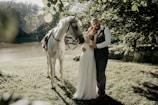 man and woman standing beside horse during daytime