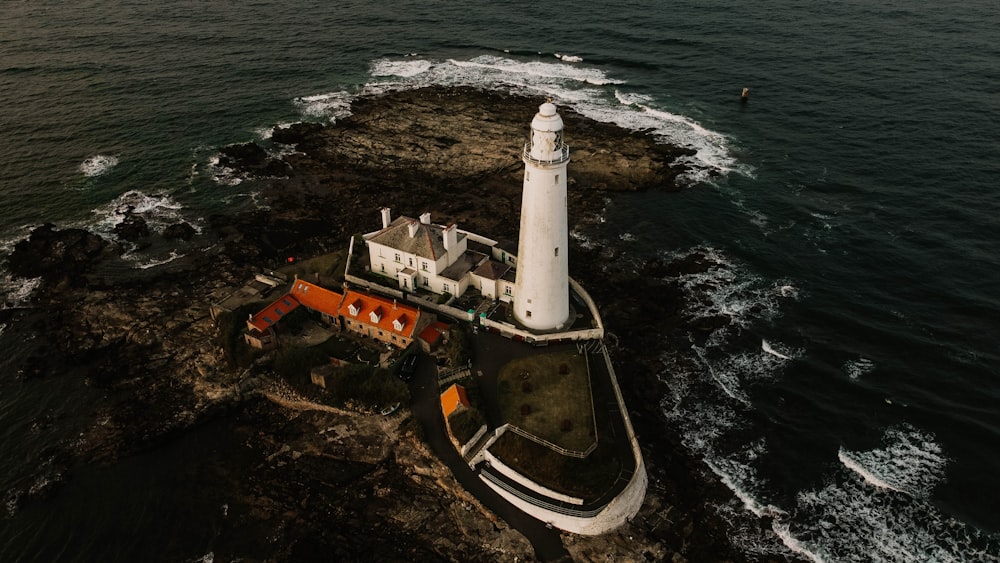 white lighthouse on brown and white land near body of water during daytime