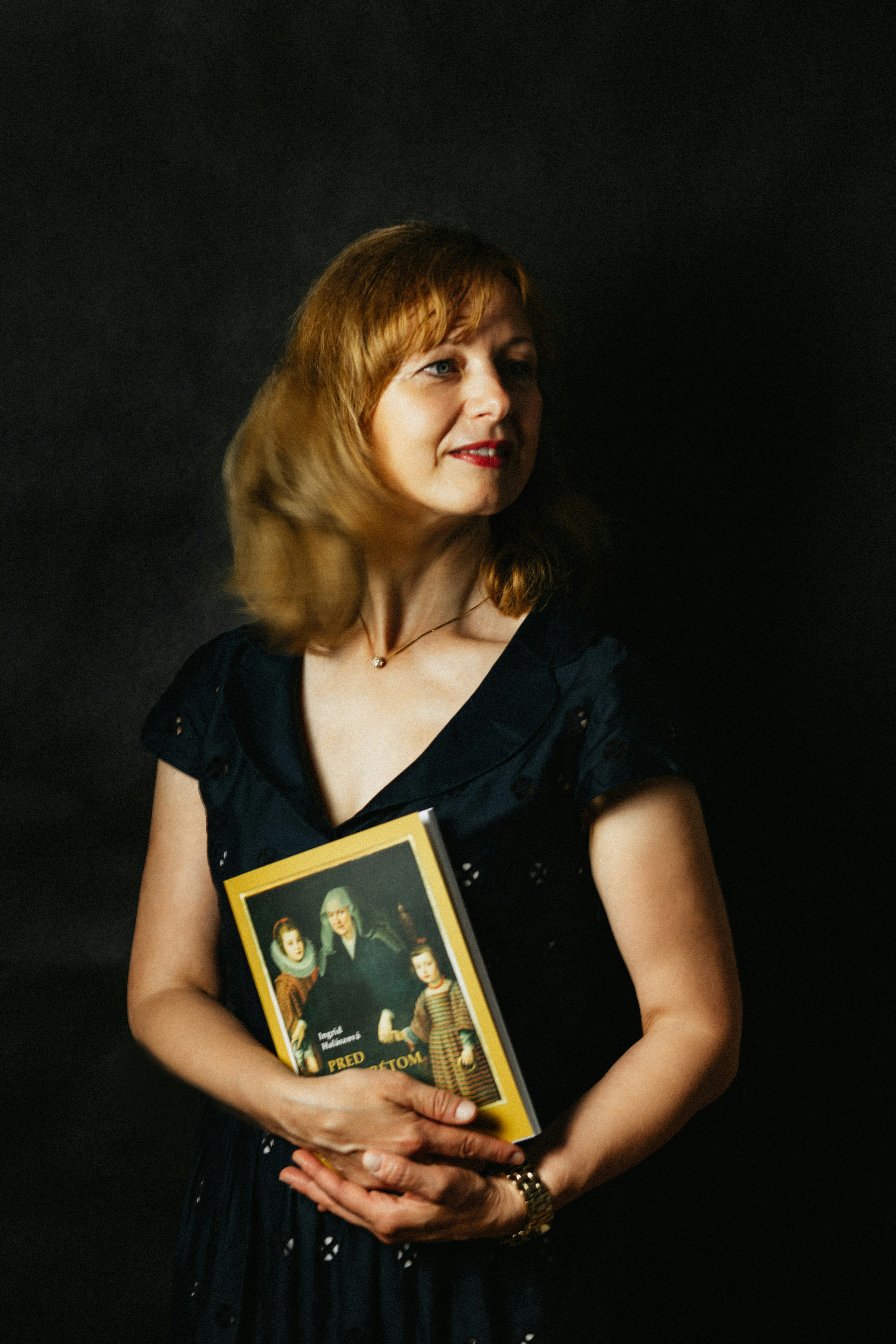 woman in black button up shirt holding black and white book