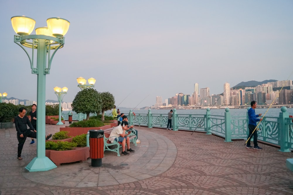 people sitting on bench near green metal railings during daytime