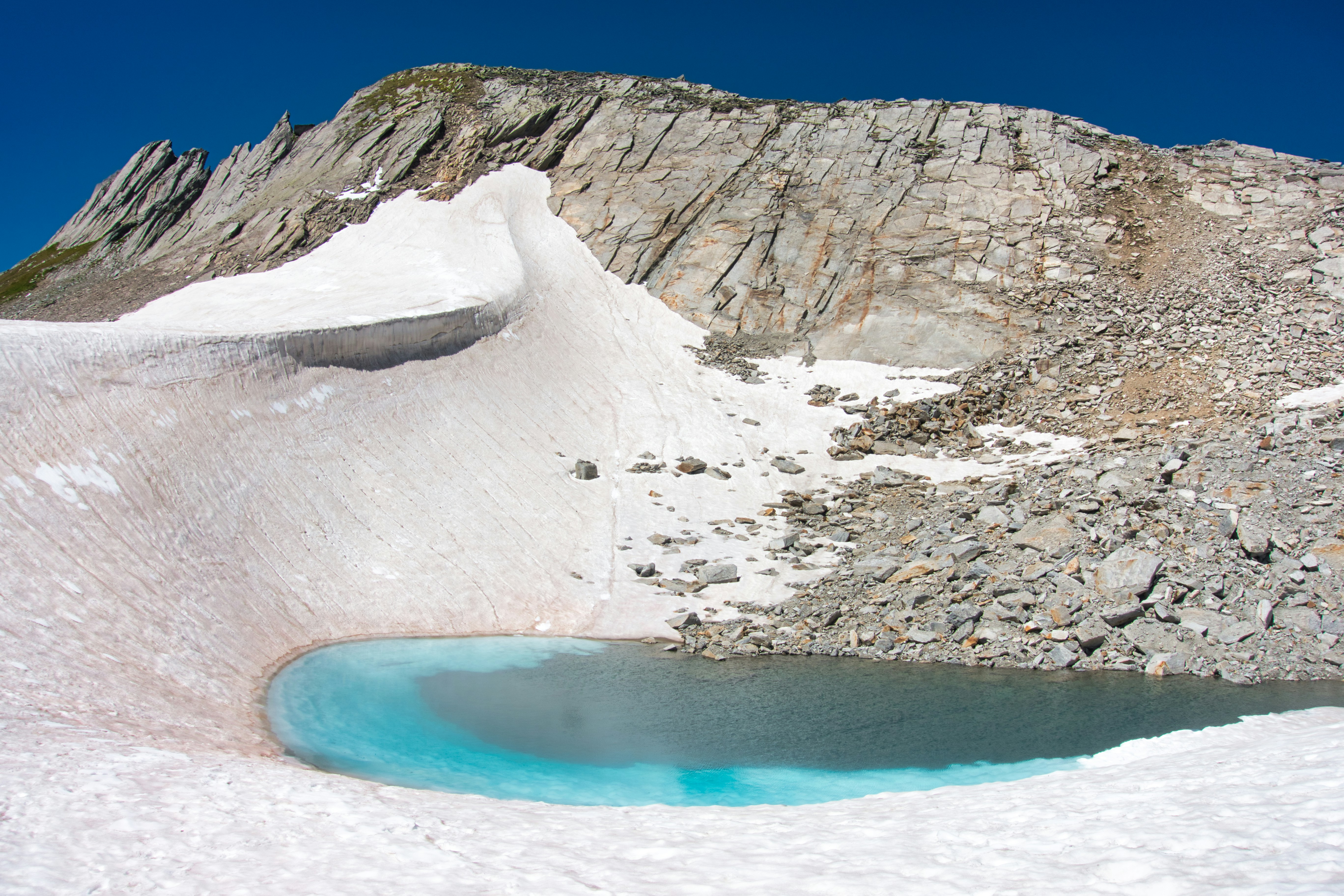 Blue glacial lake with rocky mountains located near Pizzo Gallina, Switzerland.