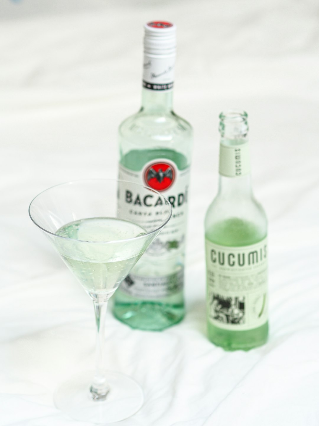 two green glass bottles beside clear drinking glass