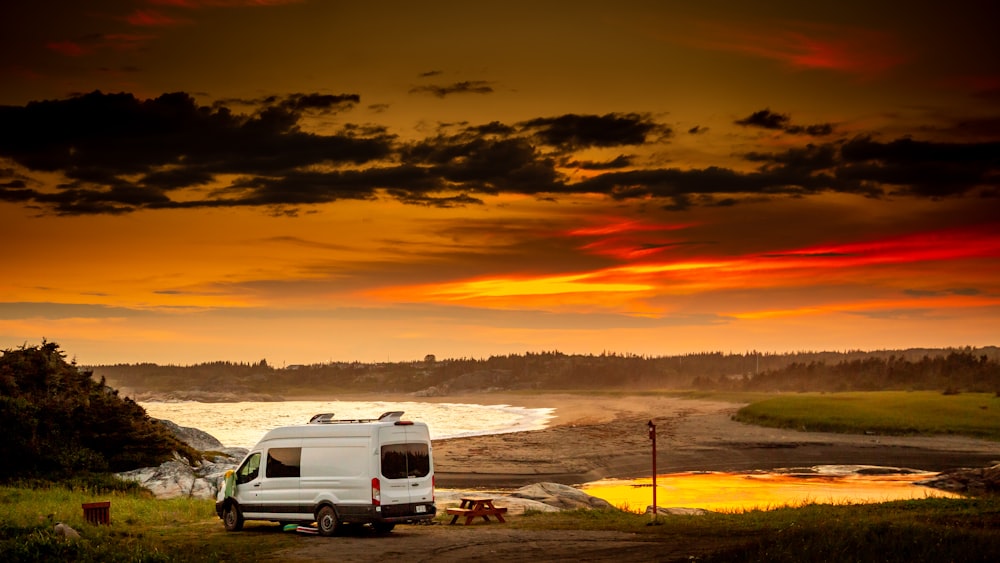 Van blanc sur un sol enneigé au coucher du soleil