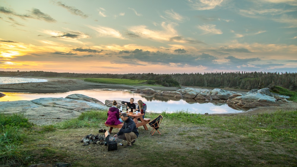 Menschen, die tagsüber auf Campingstühlen in der Nähe des Sees sitzen