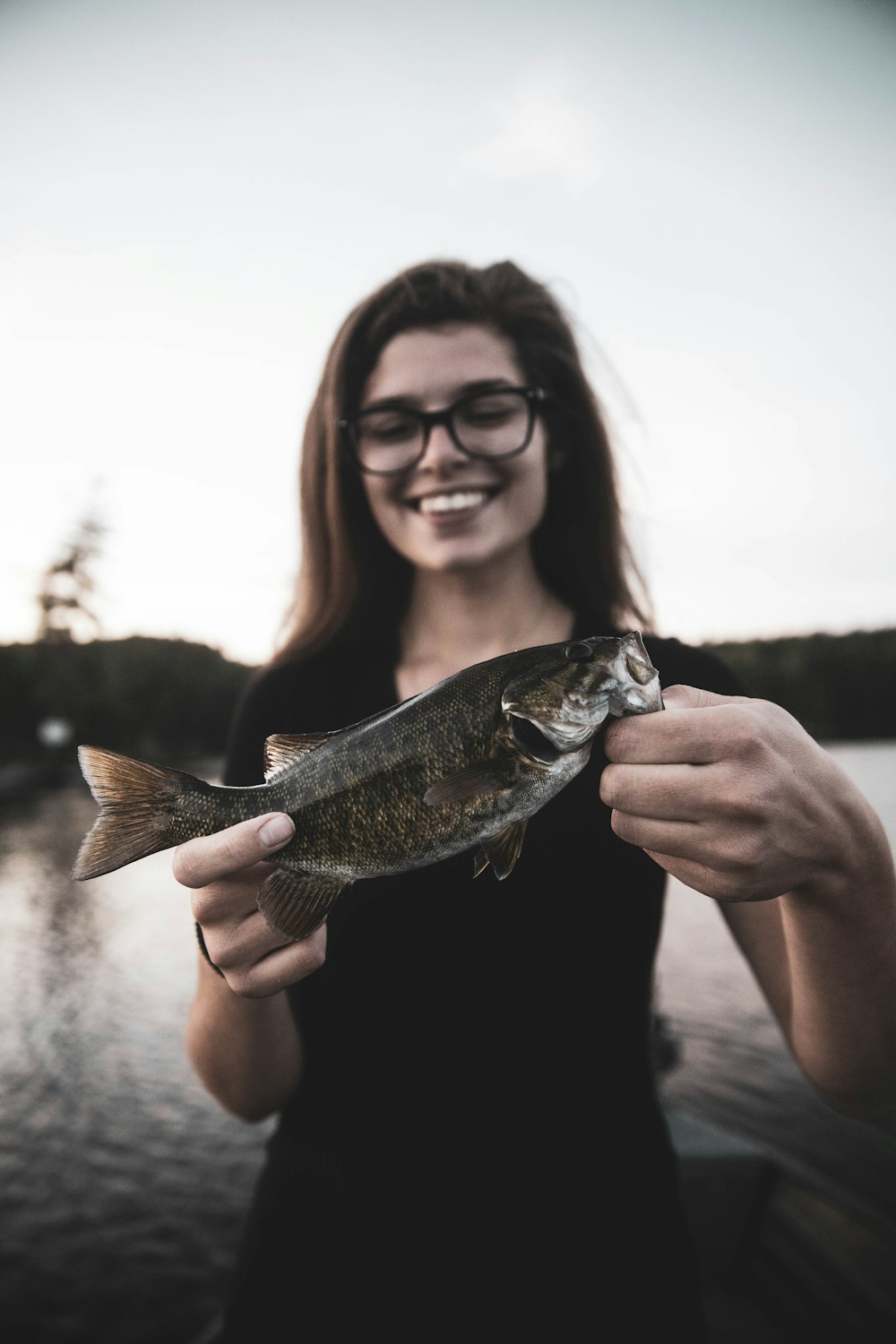 woman holding gray and white fish