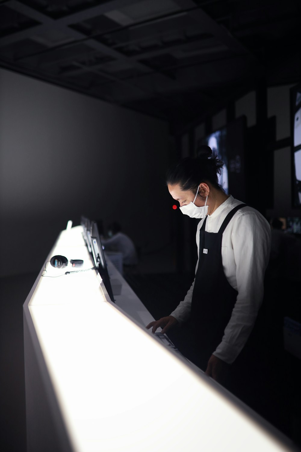 man in white shirt and black vest standing beside white table