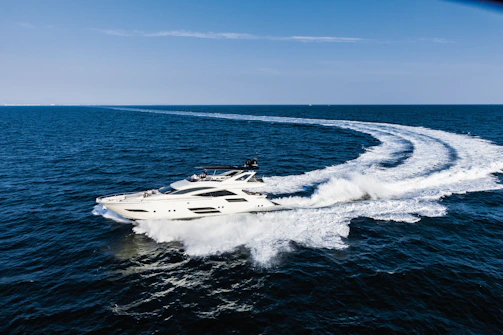 A sleek private yacht cruising on crystal-clear blue waters under a bright sky.