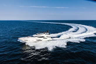A sleek yacht cruising along the coastline near Surf City, North Carolina under a clear blue sky.
