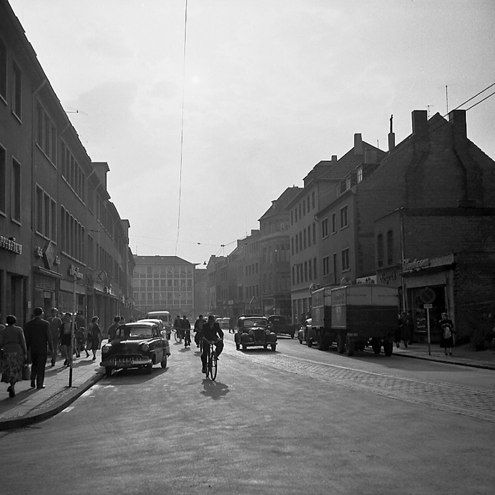 grayscale photo of man riding bicycle on road