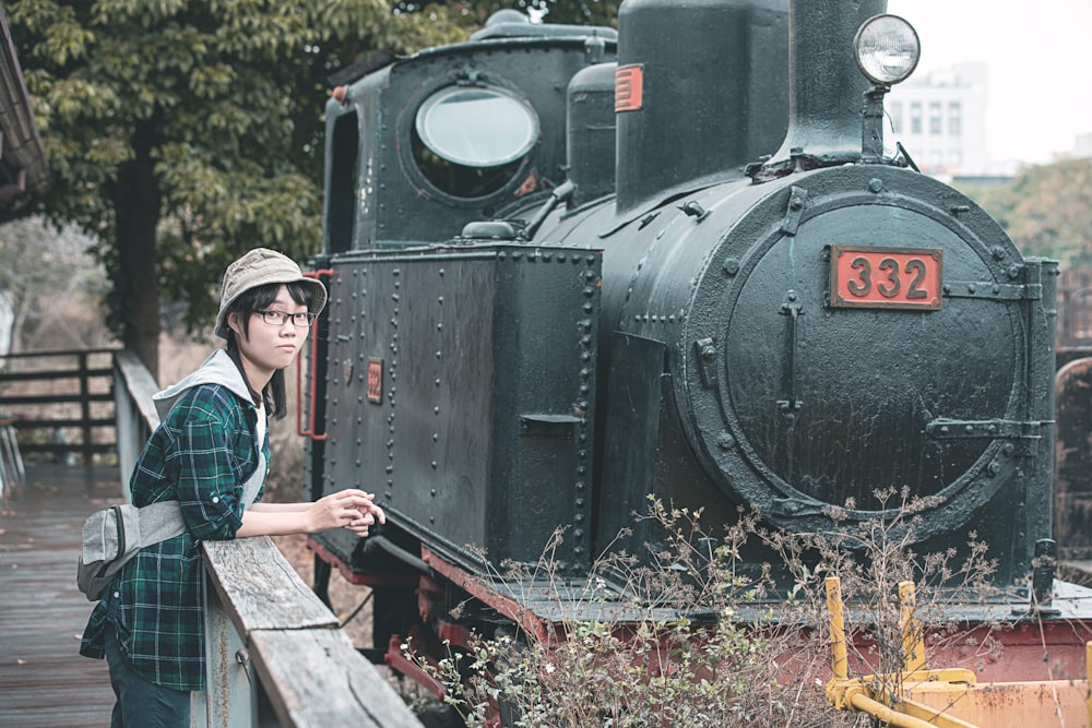 man in blue and white plaid dress shirt standing beside black train during daytime