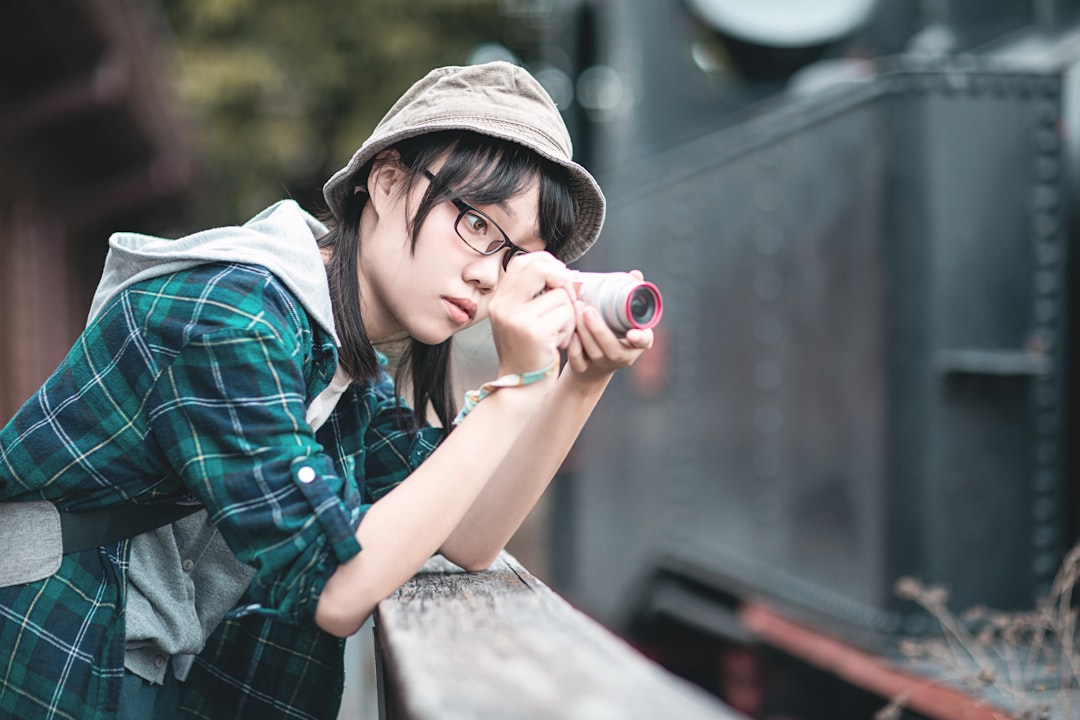 woman in blue and black plaid button up shirt holding red and black camera