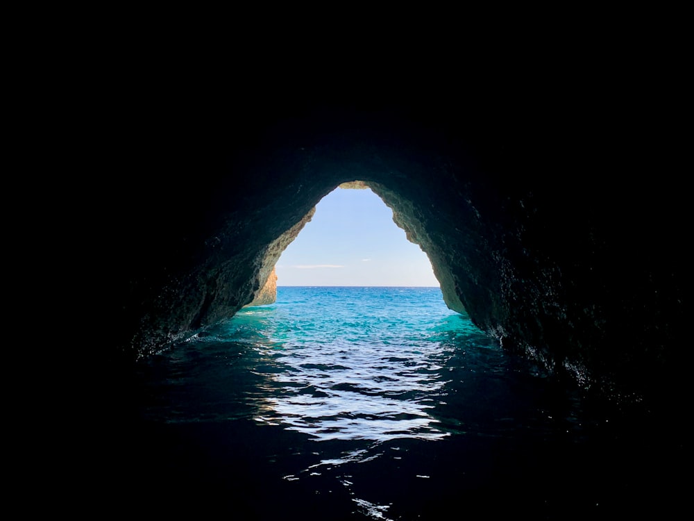 cave with body of water during daytime