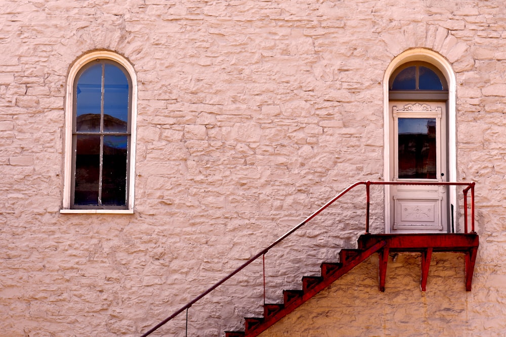 brown wooden staircase beside brown brick wall