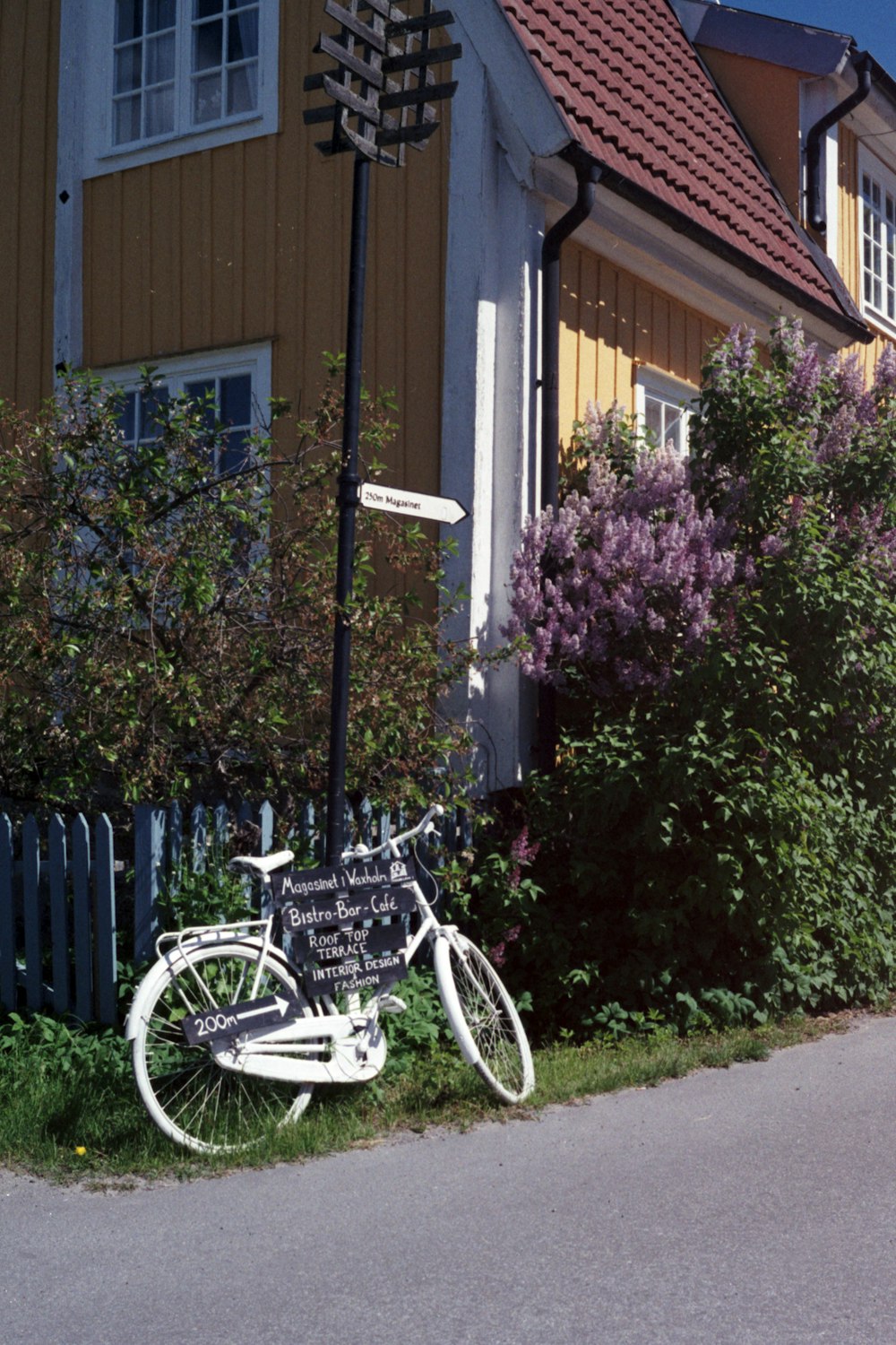 white city bike parked beside white wooden fence