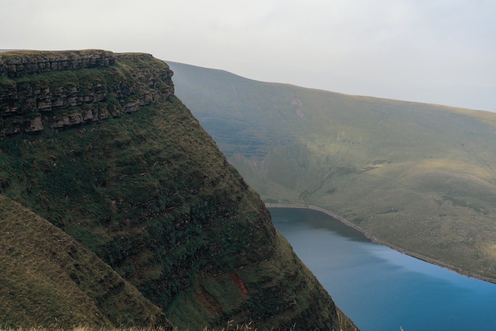 green mountain beside blue sea during daytime