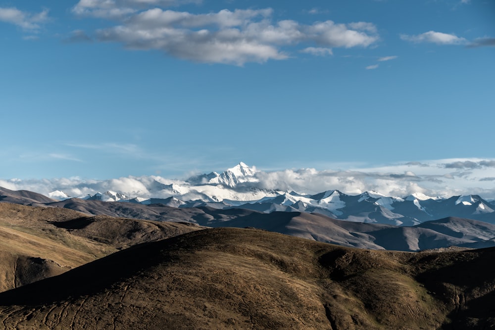 brown and white mountains under white clouds and blue sky during daytime